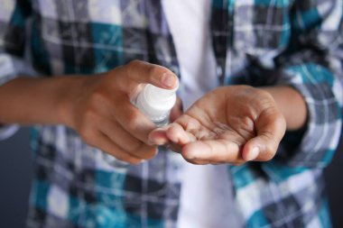 Delikanlının elini dezenfektan spreyiyle kapat..