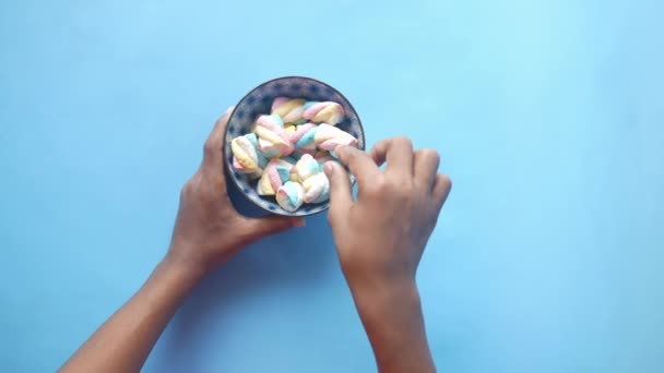 Mão escolher doces marshmallow em uma tigela em azul — Vídeo de Stock