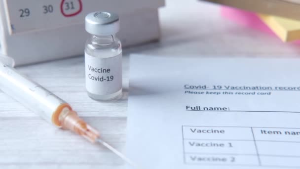 Vakcinázási rekord kártya, kézfertőtlenítő és maszk színes háttér — Stock videók