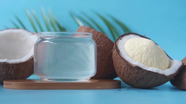 Skive fersk kokosnøtt og en flaske olje på et bord – stockvideo