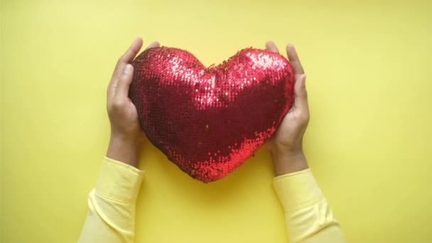 Ținând inima mare roșie pe fundal galben — Videoclip de stoc