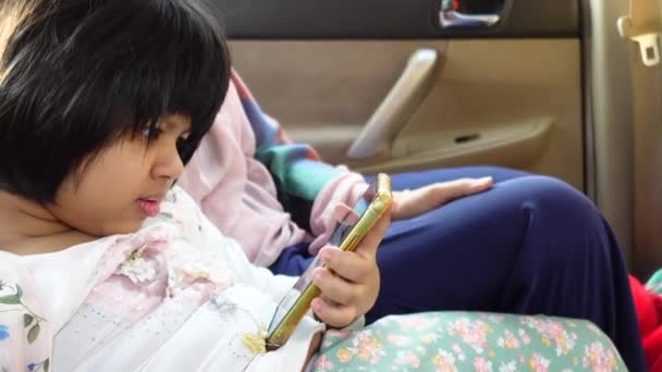 Gyermek lány néz rajzfilm okos telefon az autóban — Stock videók