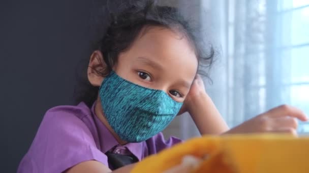 Een boos kind meisje met gezichtsmasker naar beneden kijken — Stockvideo