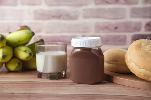 Desayuno por la mañana con crema de avellana de chocolate, plátano, pan y leche — Foto de Stock