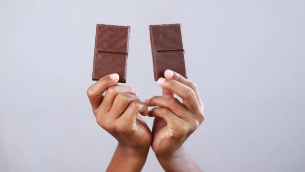 Tangan anak laki-laki memegang coklat gelap terhadap latar belakang putih — Stok Video