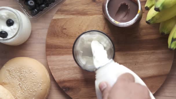 Vista superior do derramamento de leite no vidro na mesa de madeira — Vídeo de Stock