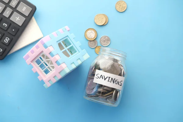 Conceito de finanças da casa com modelo de casa e frasco de moeda de poupança na mesa — Fotografia de Stock