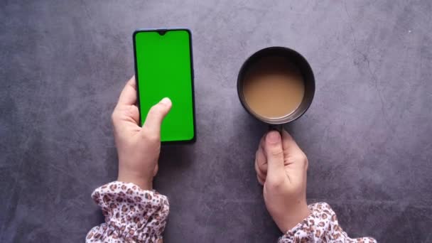 Vista de ángulo alto de la mano de las mujeres usando el teléfono inteligente y beber café — Vídeos de Stock