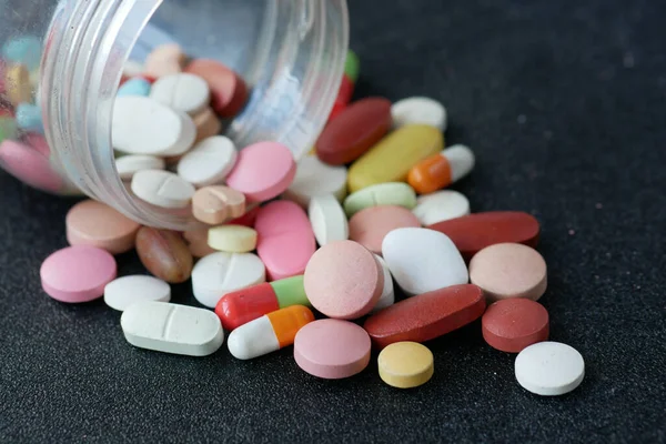 Primer plano de muchas píldoras y cápsulas de colores sobre fondo negro — Foto de Stock