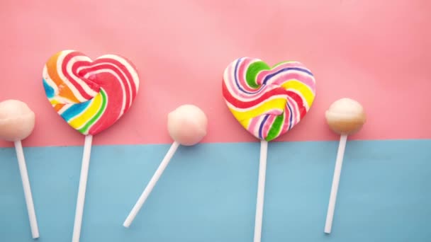 Rainbow heart shape lollipop on color background — Stockvideo