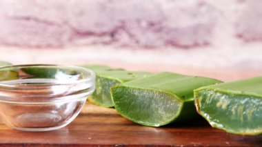 Yakın plan taze Aloe vera dilimlenmiş ve doğrama tahtasındaki bir kapta yağ var.