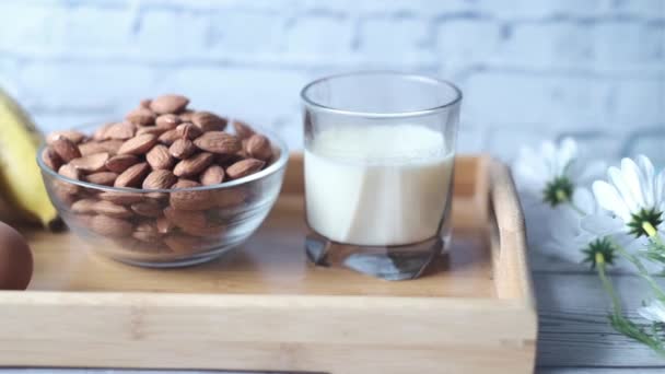 Huevos en un recipiente de plástico, leche y almendras en la mesa — Vídeos de Stock