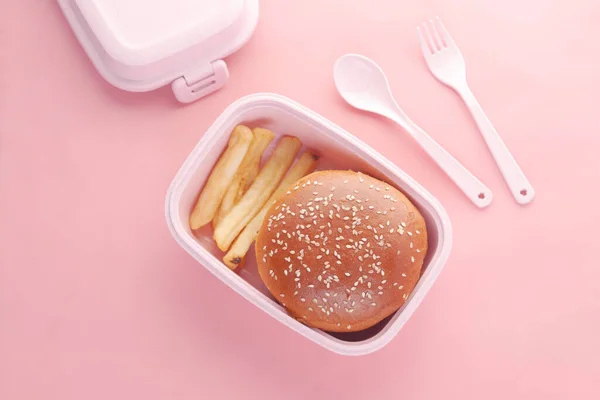 Marhahús burger és francia barát egy ebéd doboz rózsaszín háttér — Stock Fotó