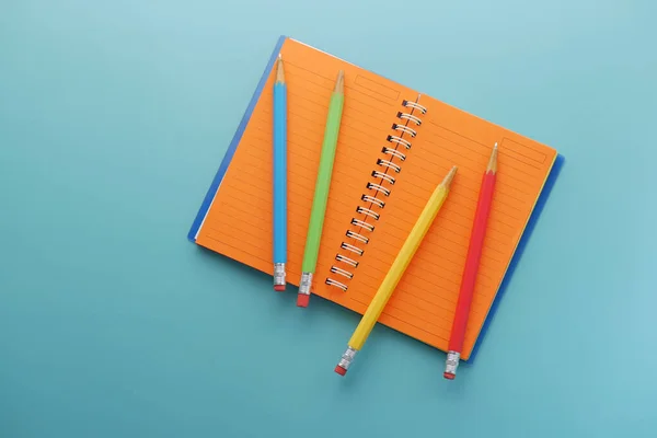 Primer plano de lápices de colores en el bloc de notas sobre fondo verde claro — Foto de Stock