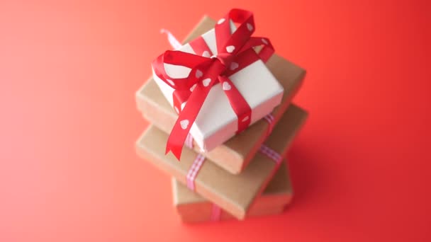 Recoger a mano g pequeña caja de regalo en forma de corazón sobre fondo rojo — Vídeos de Stock