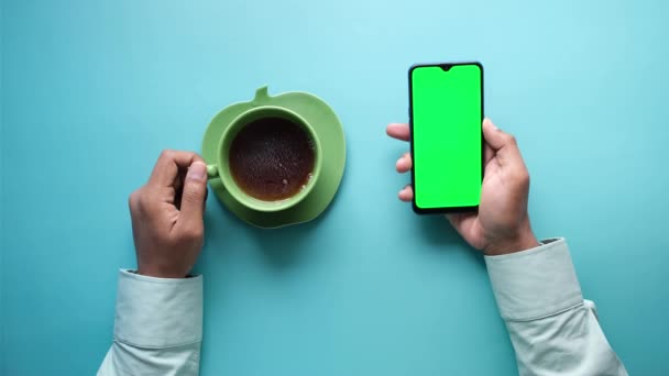 Vista de ángulo alto de la mano del hombre usando el teléfono inteligente y beber té verde — Vídeos de Stock