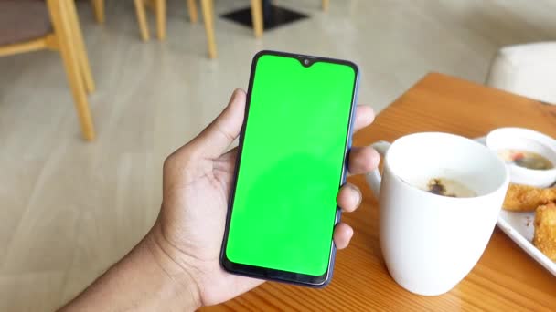 Mano joven usando teléfono inteligente con té y galletas en la mesa — Vídeos de Stock