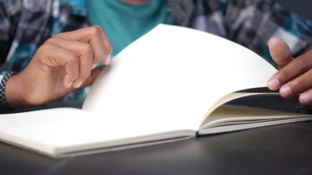 Young man turning a page of a notepad — Stockvideo