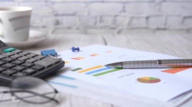 finansal grafik, hesap makinesi ve not defteri masanın üzerinde 