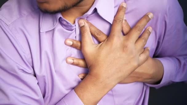 Fiatal férfi szenved fájdalom a szív és a kezében mellkasát kézzel — Stock videók