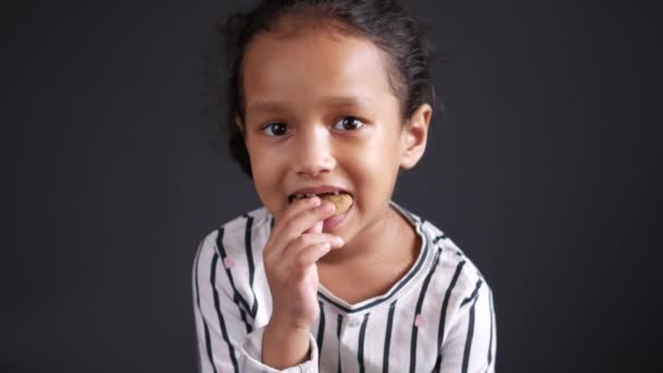 Девочка ест шоколадное печенье во время сидения — стоковое видео