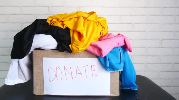 Donatie doos met donatie kleding op een houten tafel . — Stockvideo