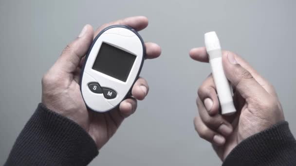 Man hand holding glucose meter on gray background — стоковое видео