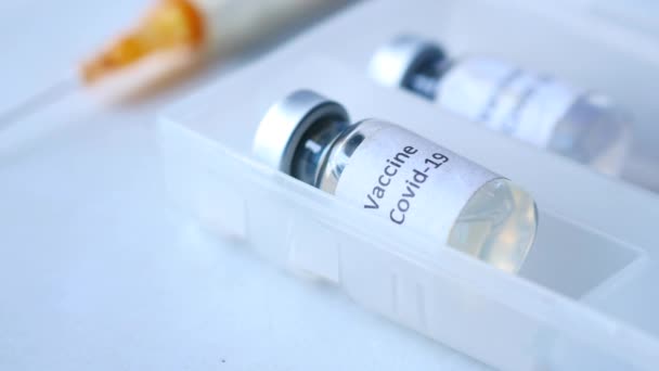 Закрытие коронавирусной вакцины в коробке и шприц на белом фоне — стоковое видео