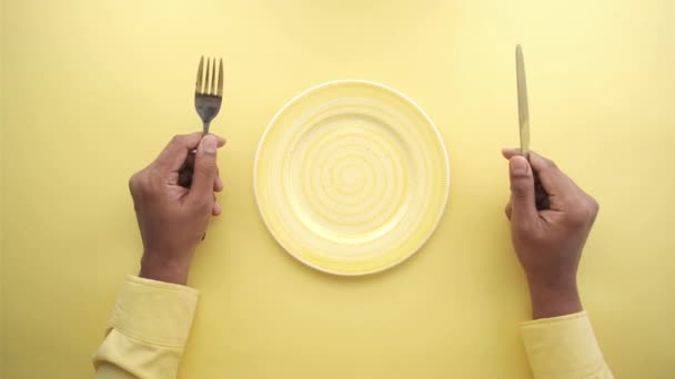 Kézben tartó evőeszközök üres tányérral a fa asztalon — Stock videók