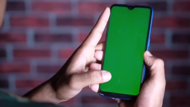 Primer plano de la mano del hombre joven utilizando el teléfono inteligente con pantalla verde — Vídeos de Stock