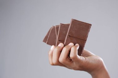 Çocuk kız, gri arka planda siyah çikolata seçiyor. 