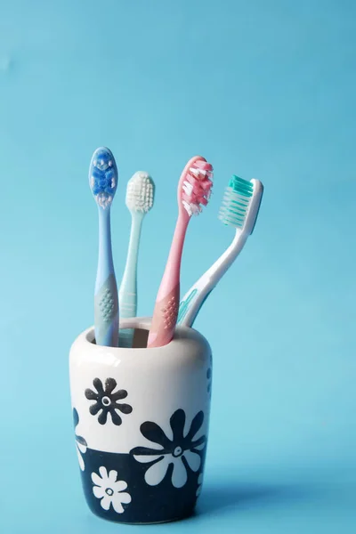 Colorful toothbrushes in white mug against blue background — Stock Photo, Image