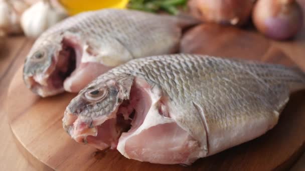 Pescado fresco crudo en una tabla de picar para prepararse para cocinar en la mesa , — Vídeo de stock