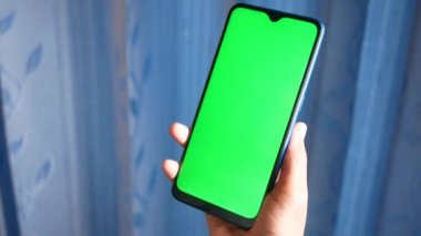 Yeşil ekranlı akıllı telefon kullanarak genç adamın elini kapat. 