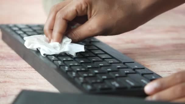 Person hand cleaning computer keyboard with a tissue on table — Stock Video