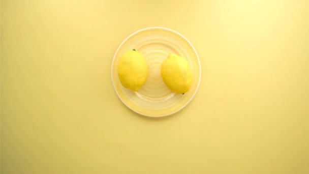 Recoger a mano Yellow Lemon de un plato sobre fondo amarillo — Vídeo de stock