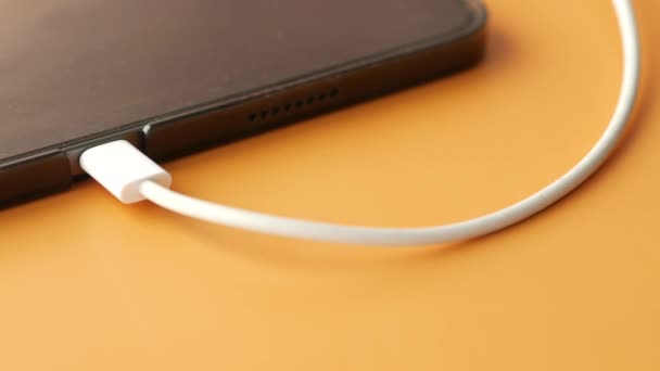 Charging digital tablet with a cable on color background . — 图库视频影像