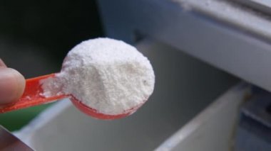 Çamaşır makinesinin plastik tepsisine çamaşır tozu dökülüyor. 