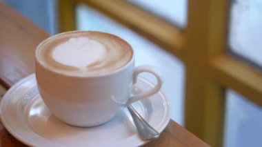 Kafenin tepesinde çiçek desenli geç kalmış bir fincan kahve. 