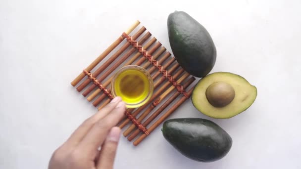 Oil and slice of avocado on white background top view — Stockvideo