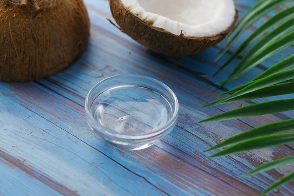 Plasterek świeżego kokosa i butelka oleju na stole — Zdjęcie stockowe