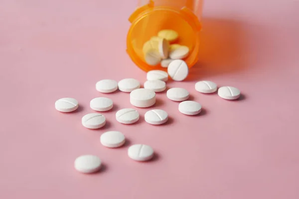 Píldoras médicas de color blanco derramamiento en rosa — Foto de Stock