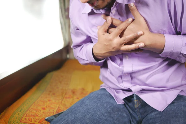 Jonge man lijden pijn in het hart en houden borst met de hand — Stockfoto