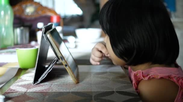 Child girl watching cartoon on tablet while sited — Stock video