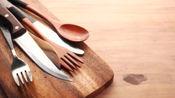 Wooden chopping board , knife, spoon and fork on table — Stockvideo