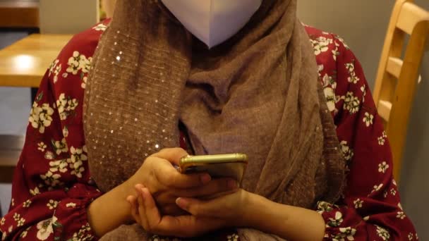 Молодые женщины в маске с помощью смартфона в кафе — стоковое видео