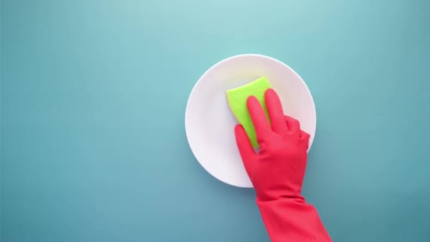 Schwamm, Gummihandschuhe und bunter Teller auf blau — Stockvideo