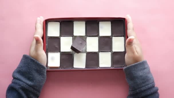 Child hand pick dark and white chocolate in a box — Stockvideo