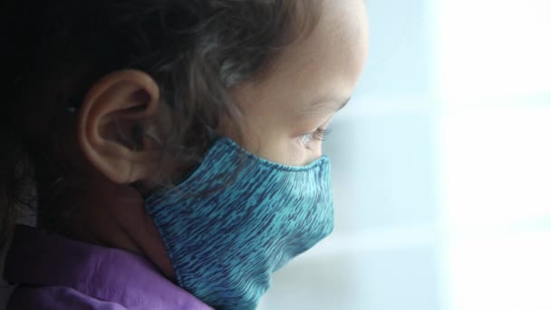 Un bambino sconvolto ragazza con maschera viso guardando in basso — Video Stock