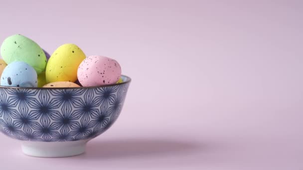 Velikonoční koncept s vícebarevným vejcem na růžovém pozadí. — Stock video